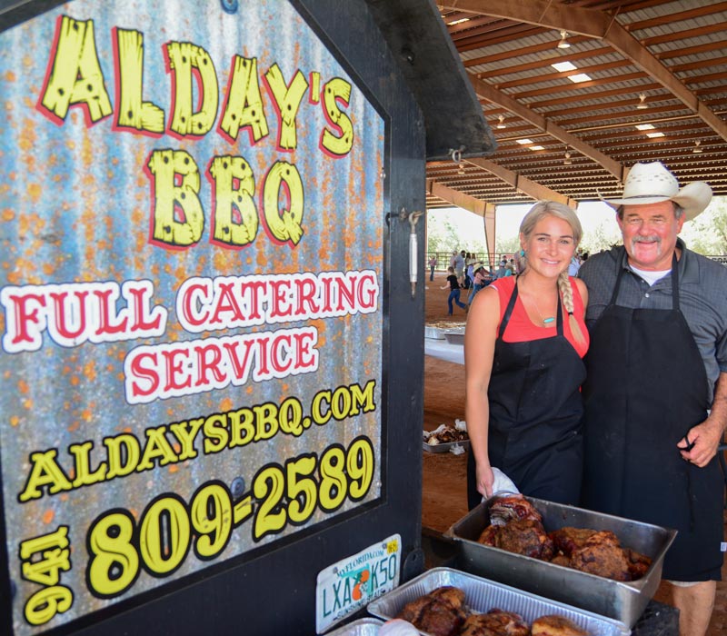 owners posing next to business sign